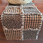 Patchwork table runner with floral and plaid patterns on a wooden table.