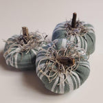Three fabric pumpkins with striped patterns on a light background