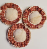 Three round fabric coasters with a checkered border on a light background